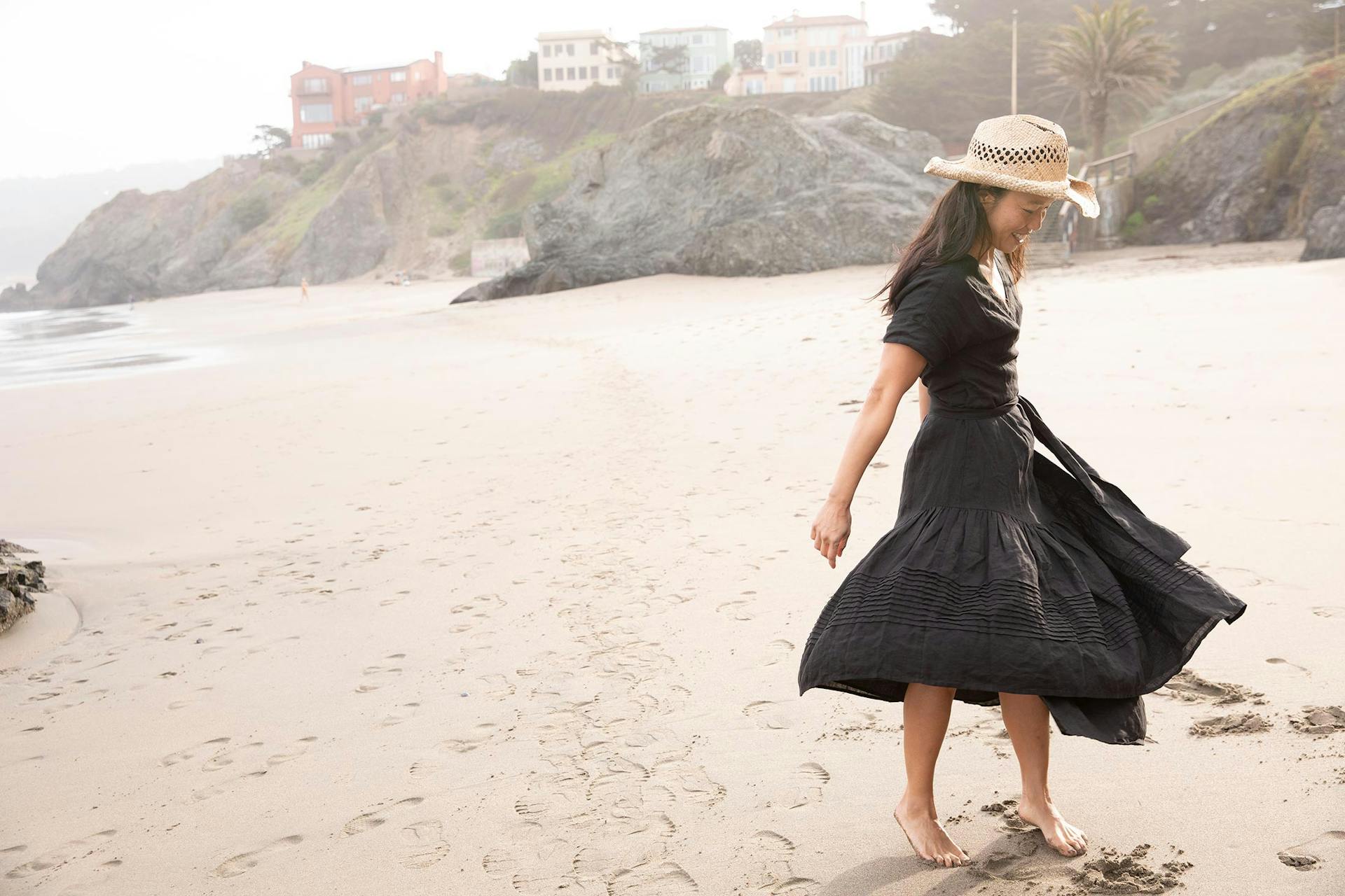 Bonnie Tsui wears a black dress and stands on the beach