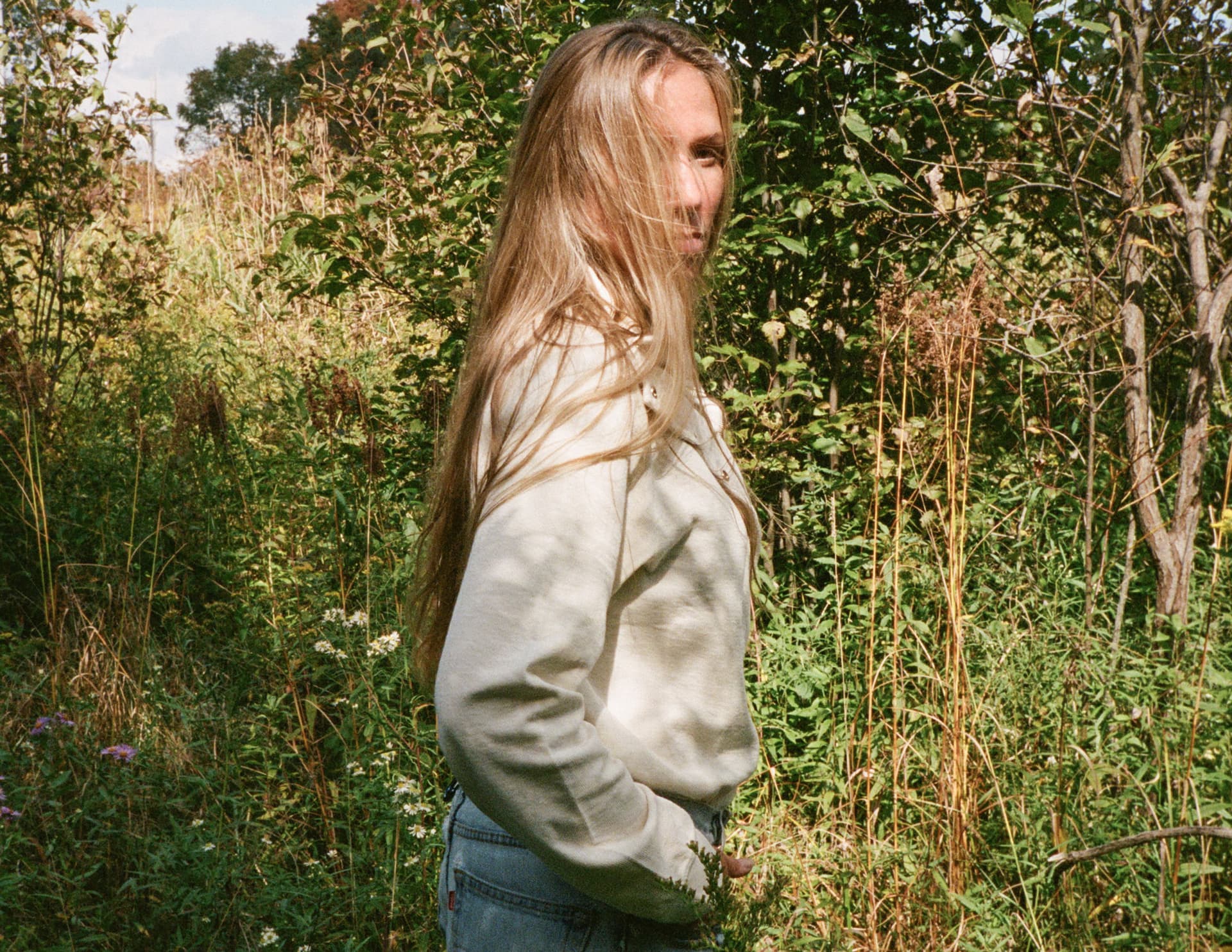 Colleen Herman stands in a sweater and jeans outside