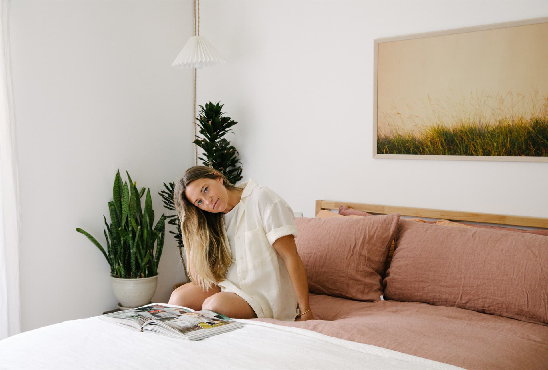 Julie Pointer Adams wears white and sits on a bed