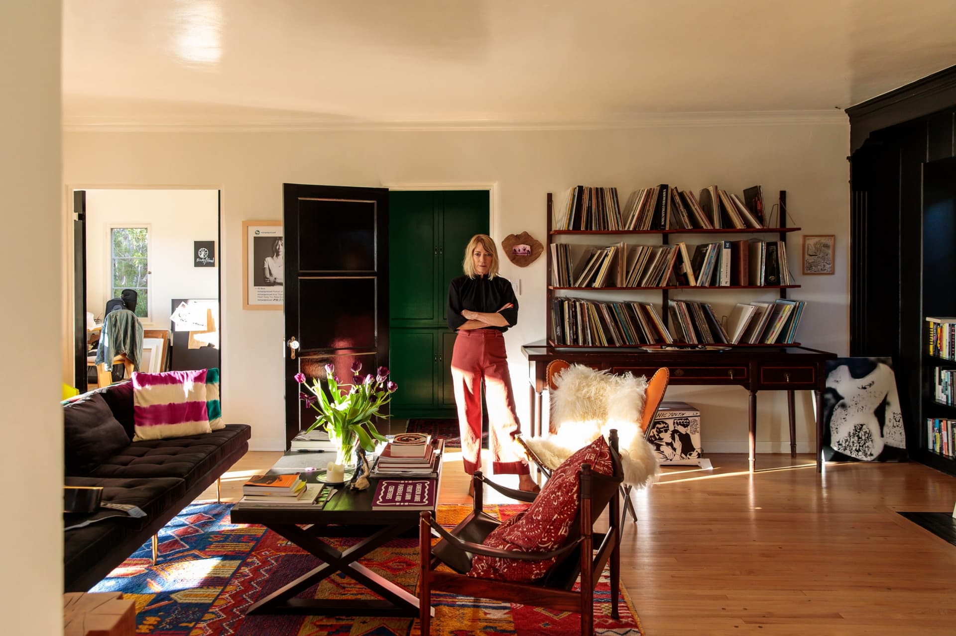 Kim Gordon stands in black top and red skirt