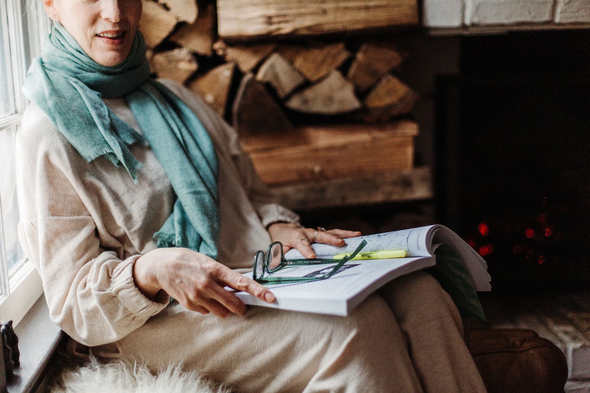 Laura Silverman wears a light outfit and a blue scarf while reading
