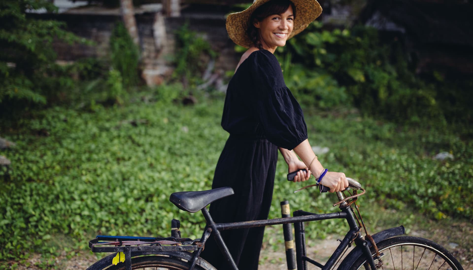 Taryn Elledge-Penner wears a black dress and holds a bike