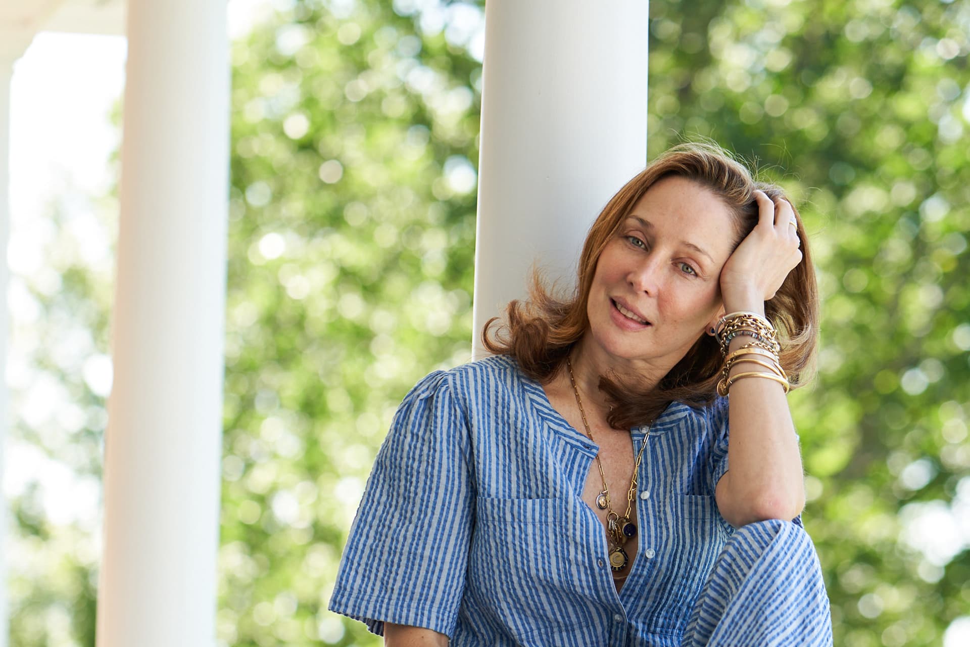 Tata Harper wears a blue outfit and sits outside