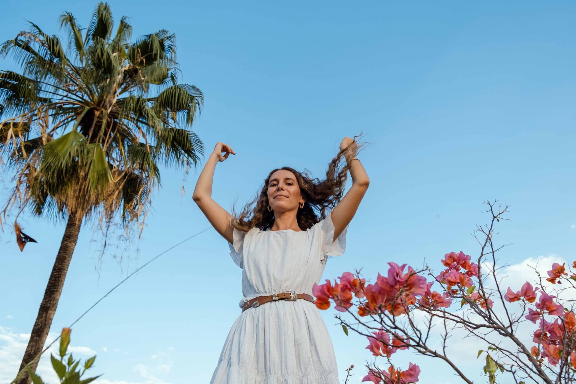 Vera Claire stands in a light dress in front of the sky