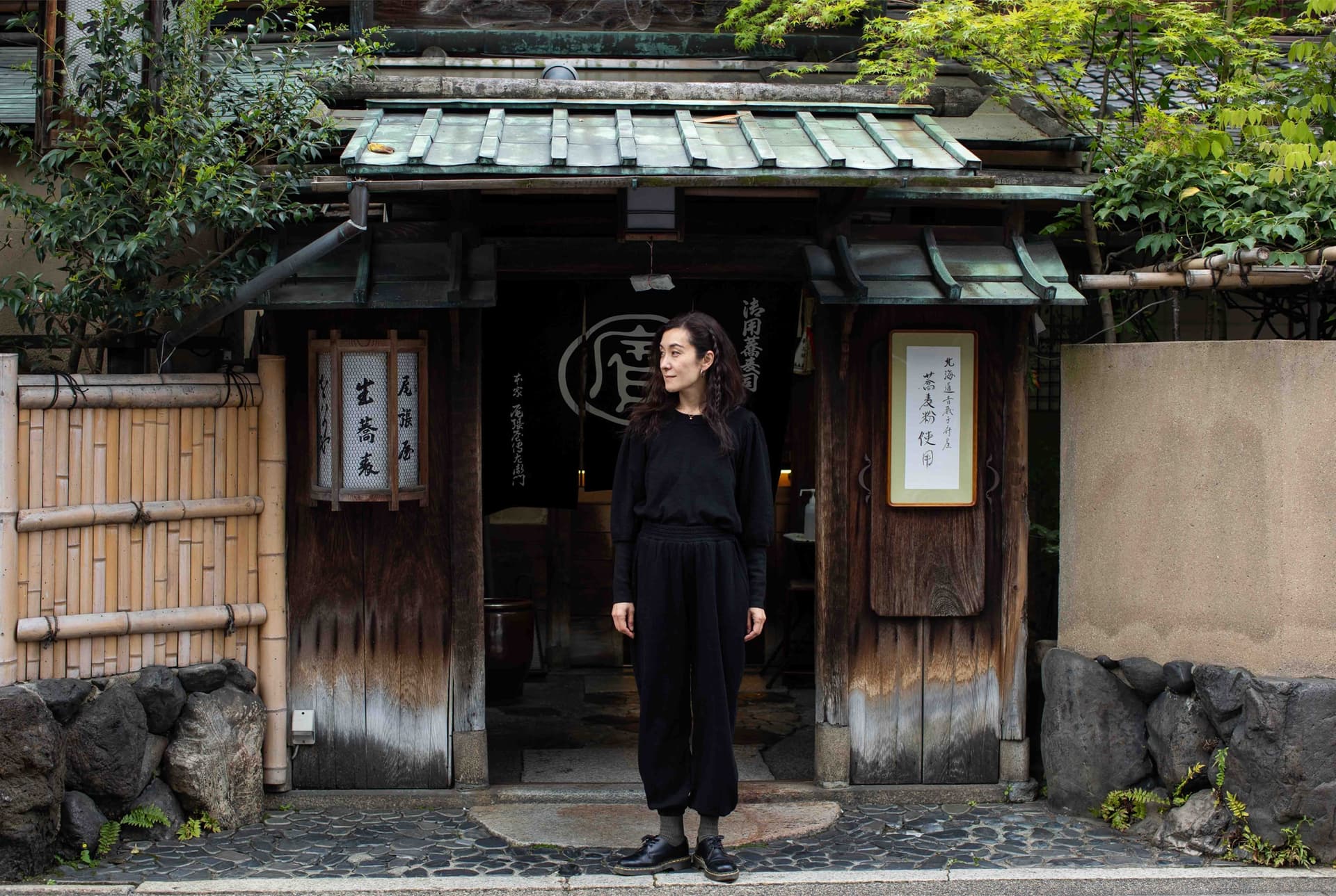 A woman wearing all black stands outside.