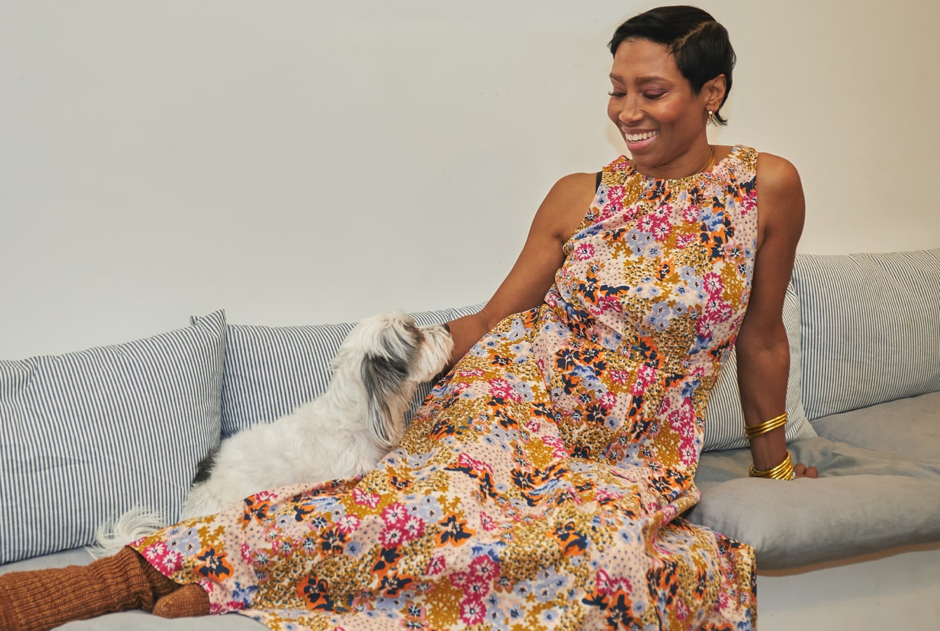A woman wearing a patterned dress lays on a couch.