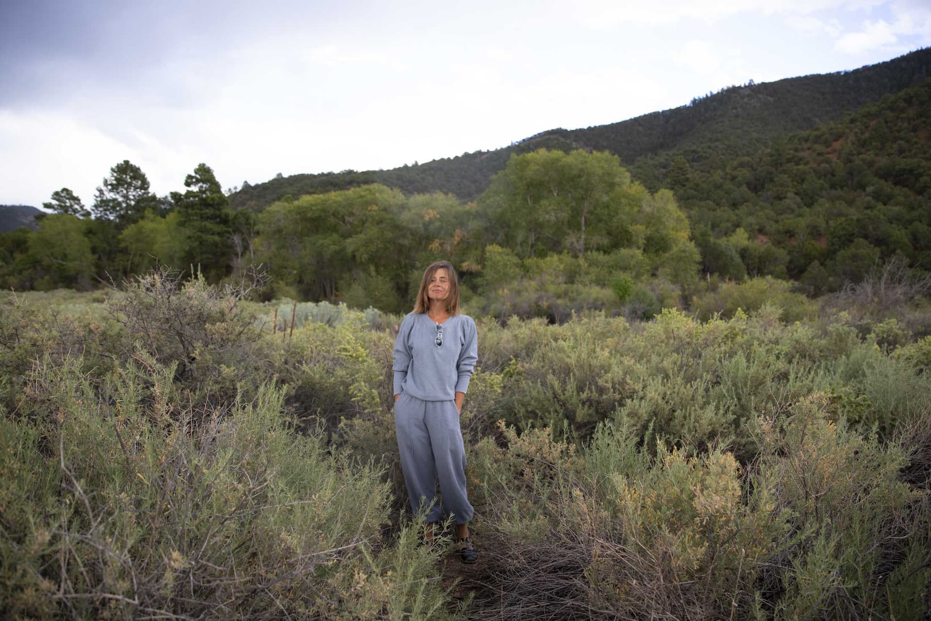 A woman wearing a blue outfit stands in a field.