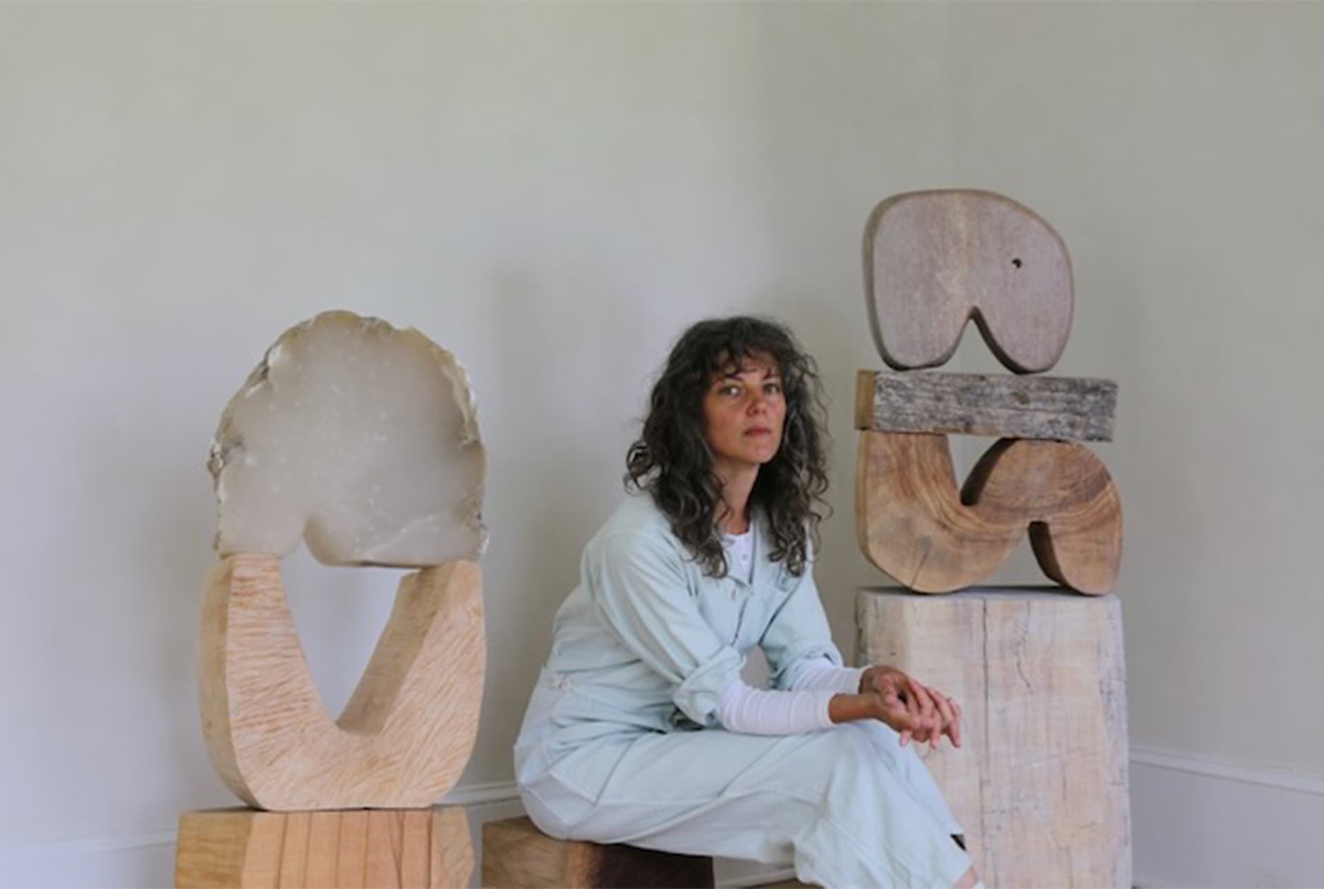 A woman wearing a light outfit sits on wood