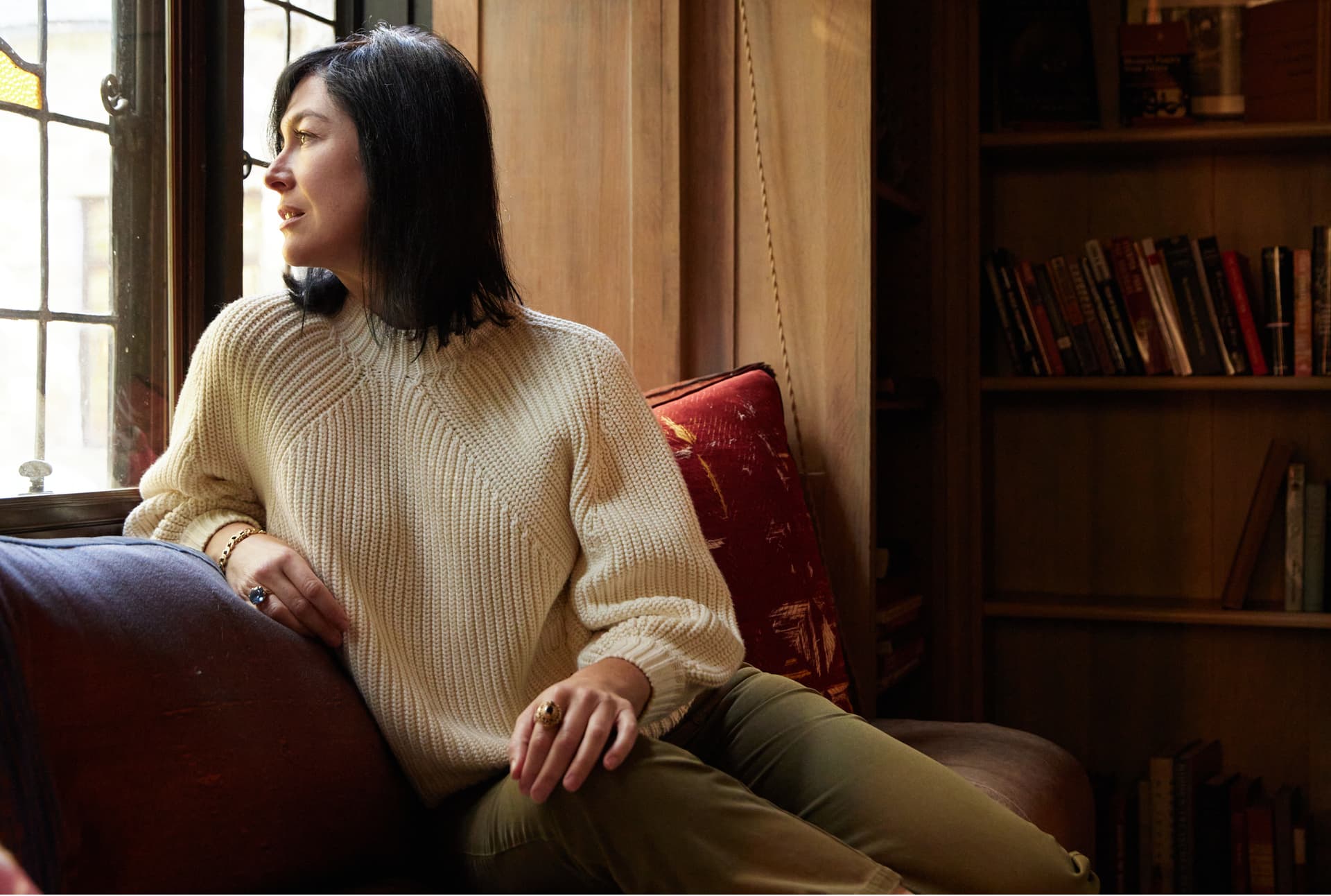 A woman wearing a white sweater sits on a couch.